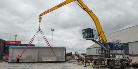 Crane lifting a unit with work people around it